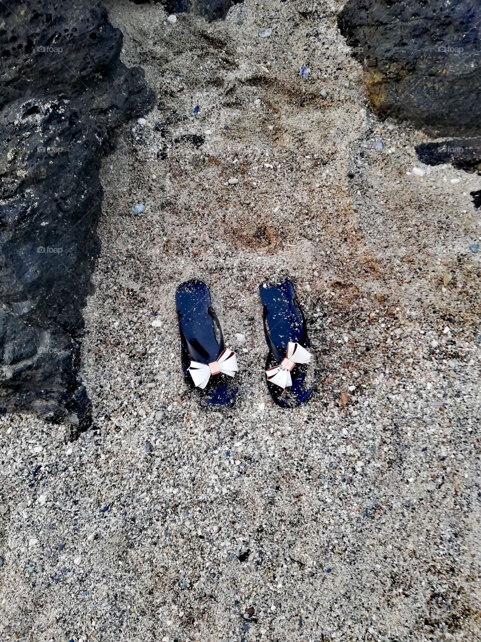 Ted Baker flip flops in sand surrounded by volcanic basaltic rock