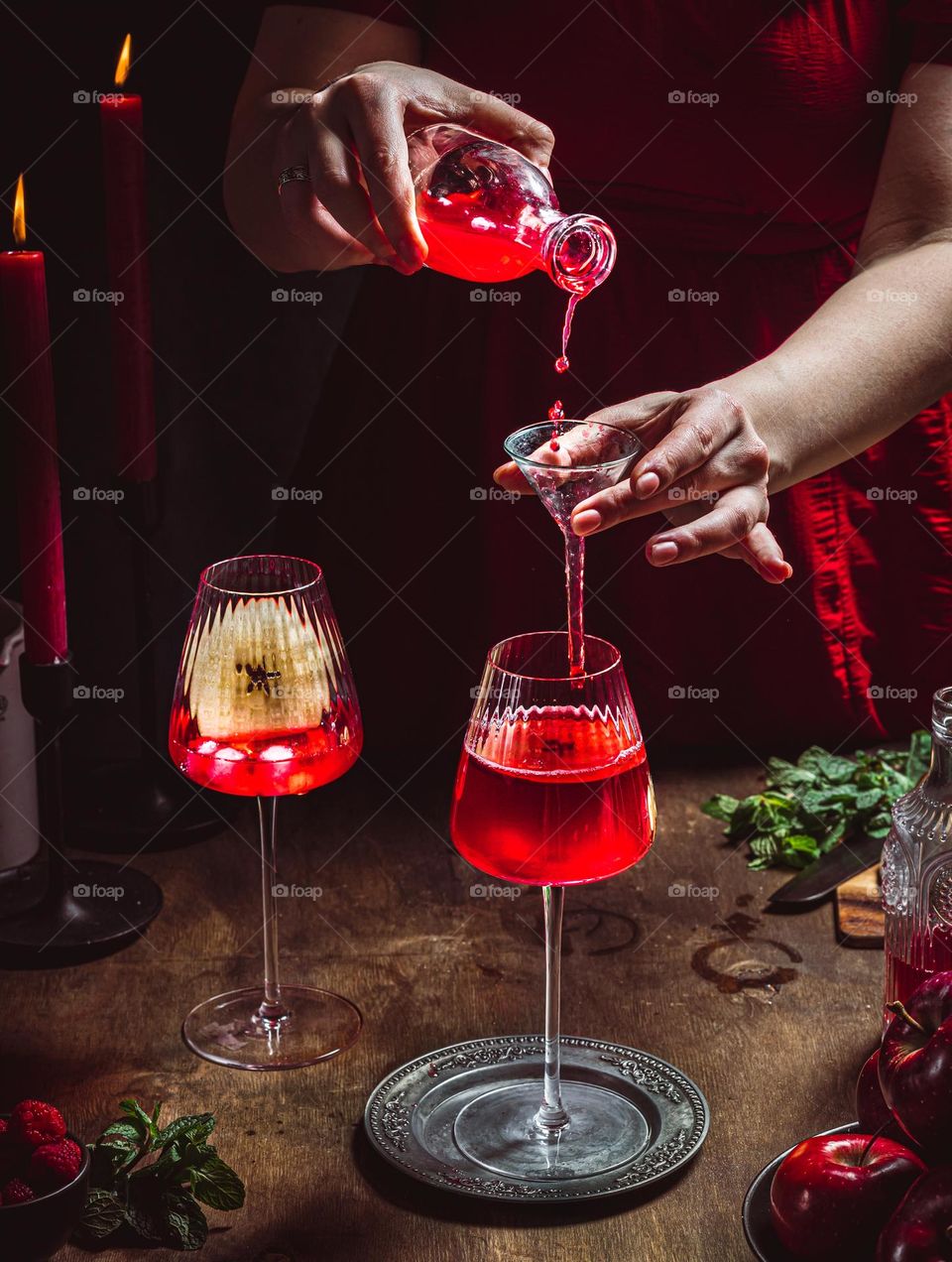 Woman prepares cozy red berries cocktail with red apple