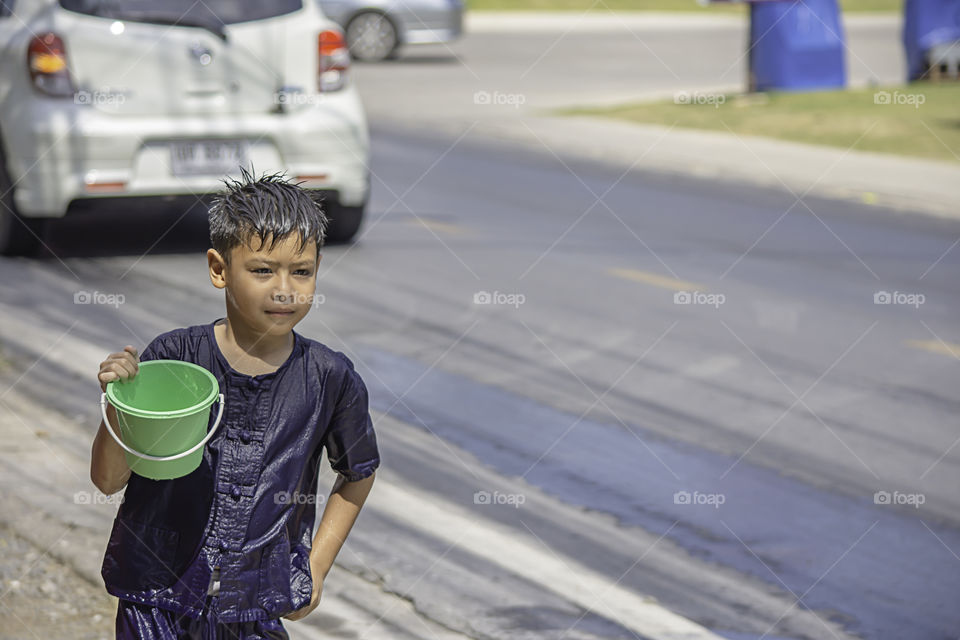 Asian boy holding Plastic bucket play Songkran festival or Thai new year in Thailand.