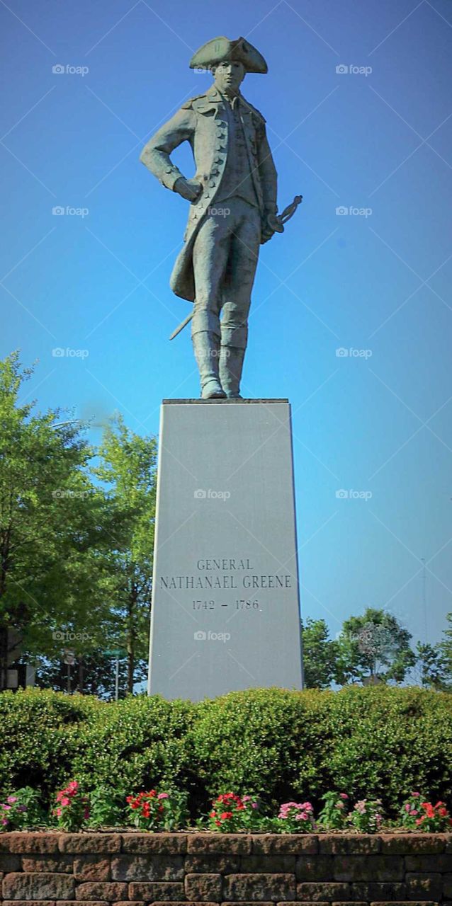 Statue of General Nathanael Greene with flowers and greenery.