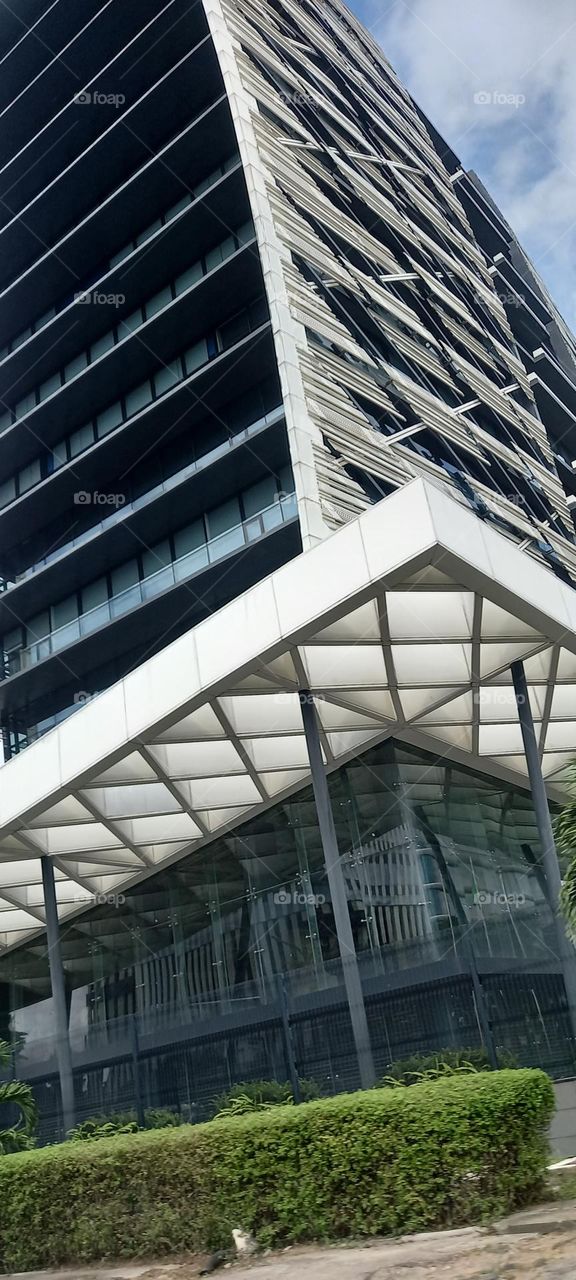 Beautiful urban office skyscraper with green plants surrounding the building.  An architectural masterpiece