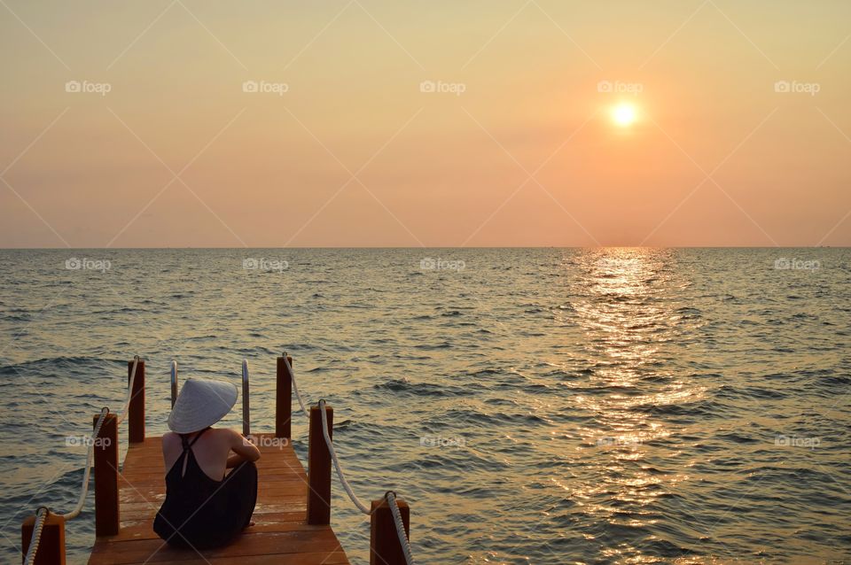 Young girl watching the sunset at a pier in Vietnam