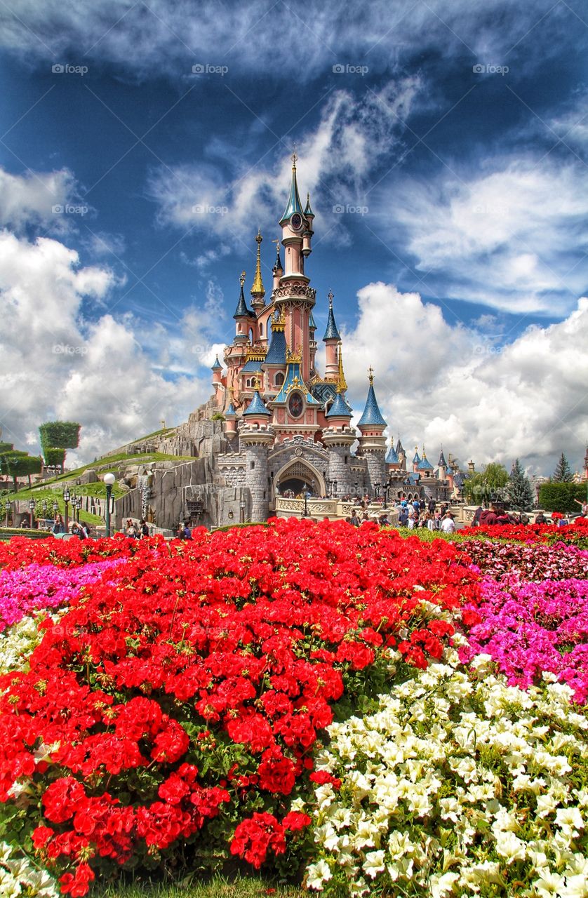 Disneyland Paris. Cinderella's castle at Eurodisney with bright and colourful flowers in the foreground.