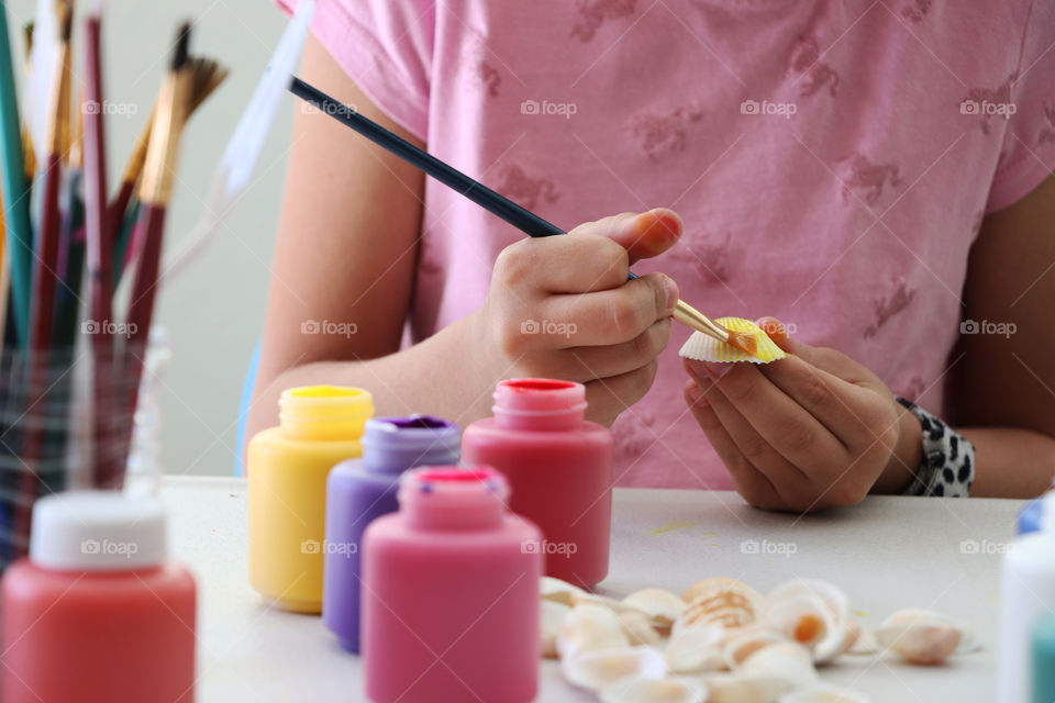 Child painting white seashell