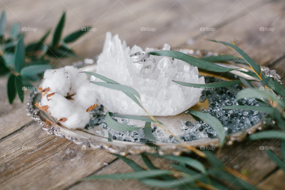 Silver plate with two wedding ring and white crystal on wood background.