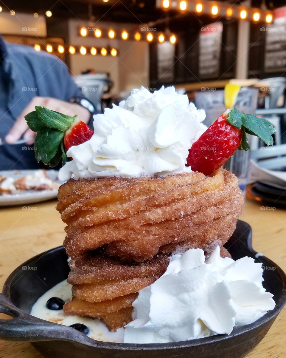 Dessert topped with whipped cream and strawberries on a small skillet