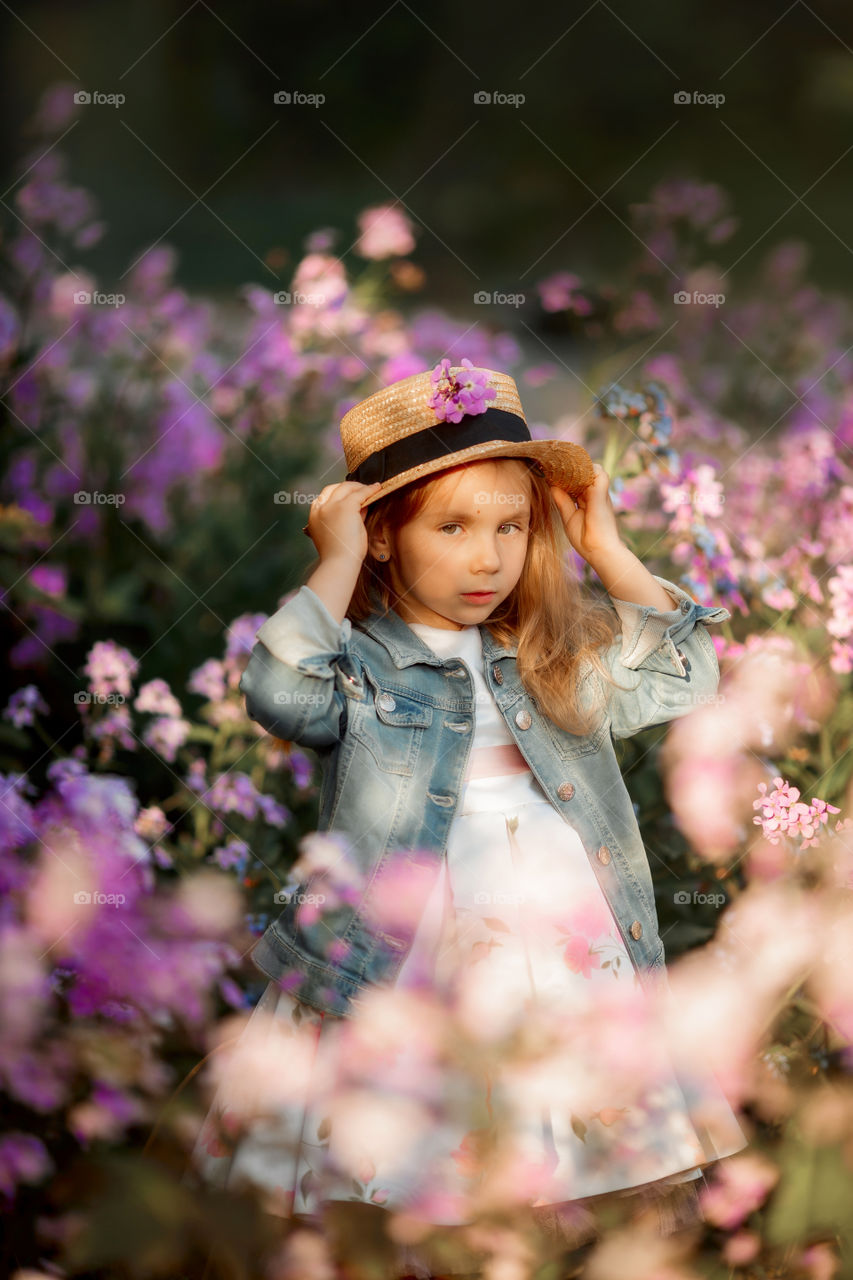 Cute little girl portrait in blossom meadow at sunset 