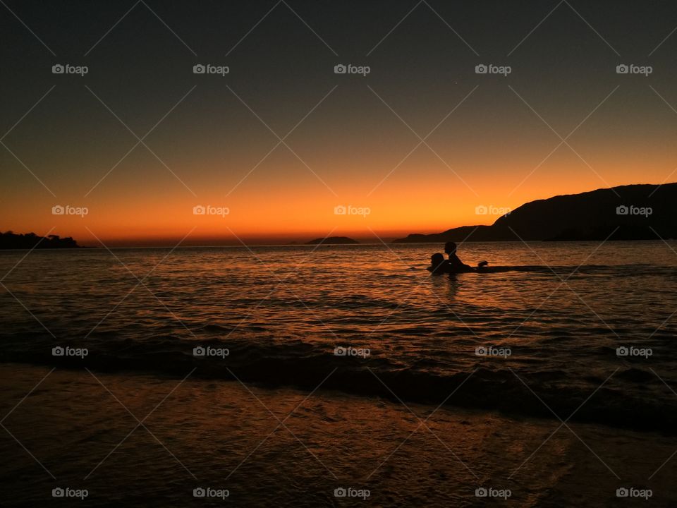 A father and his son . In the Ilhabela sunset in Brazil a dad sails with his boy in the neck like a dolphin. 