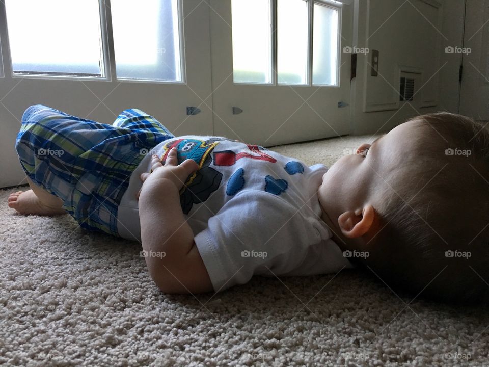 Baby boy on floor looking out of window.