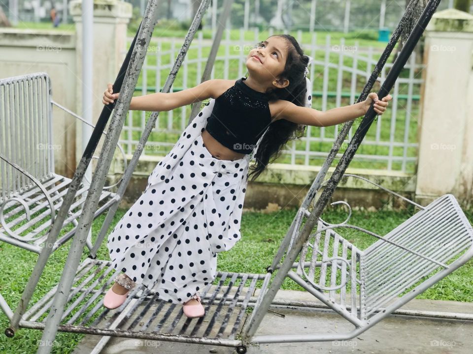 Beautiful baby girl swinging on iron swing 