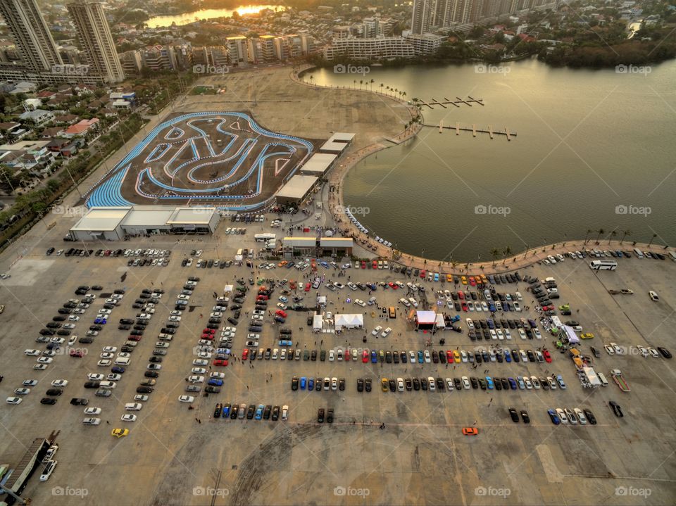 drone aerial view from above of cars parked next to a lake and go kart circuit