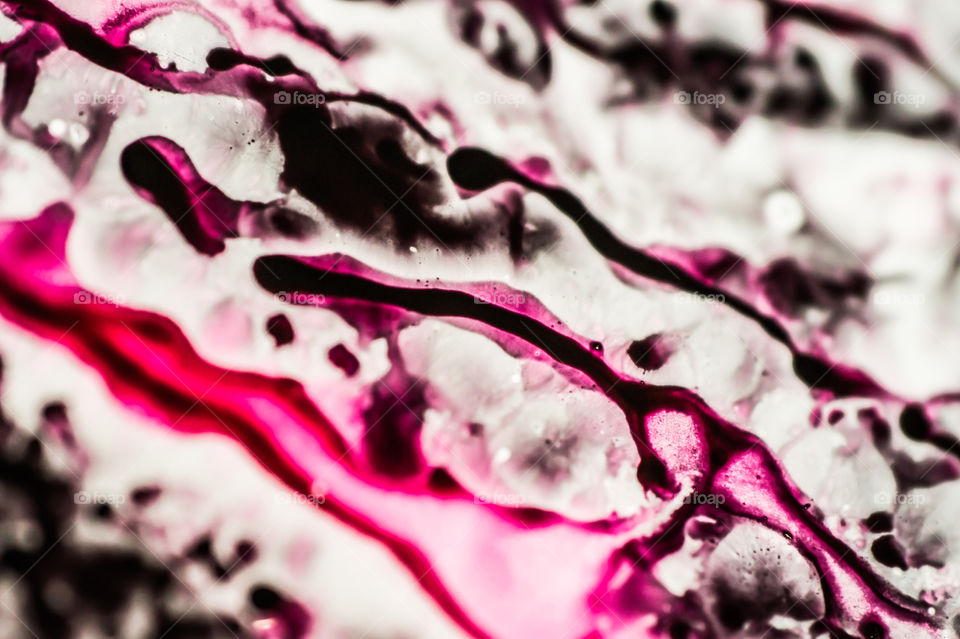 Black and pink refill ink spilled onto the white sink and the ink mixed into abstract blobs and patterns.