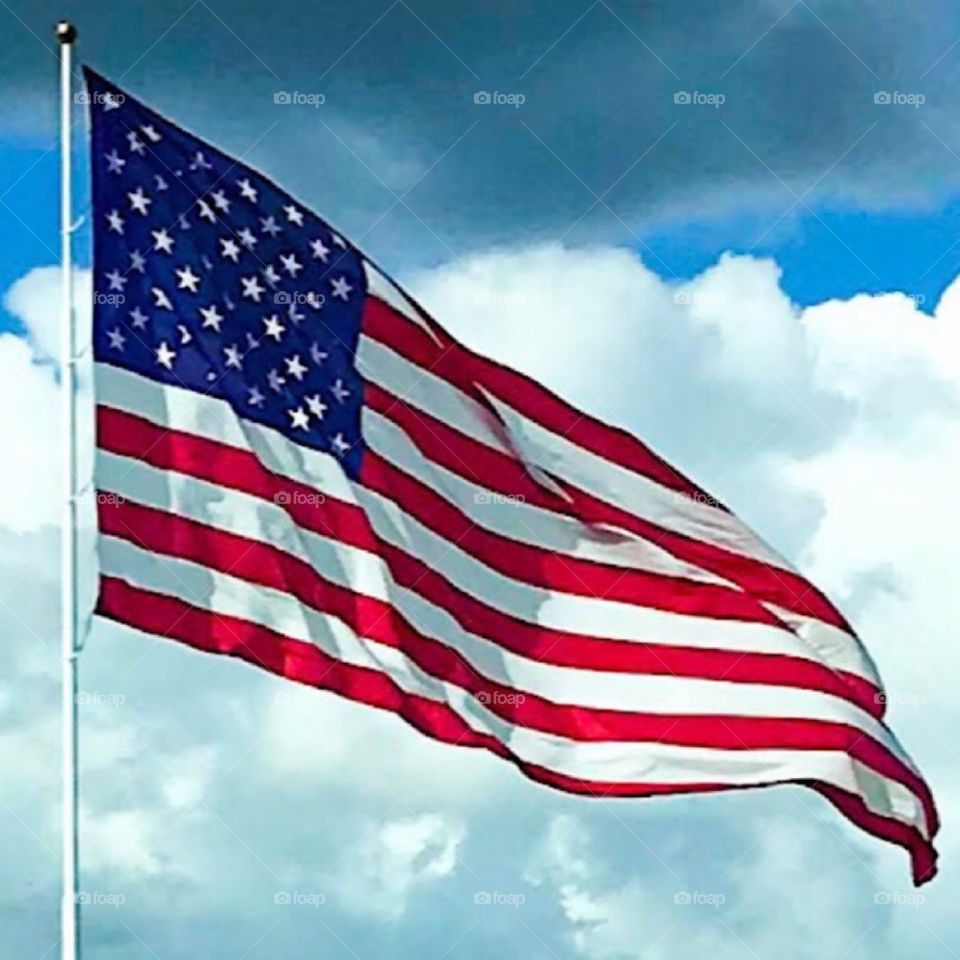 Large American United States flag with sky and clouds background