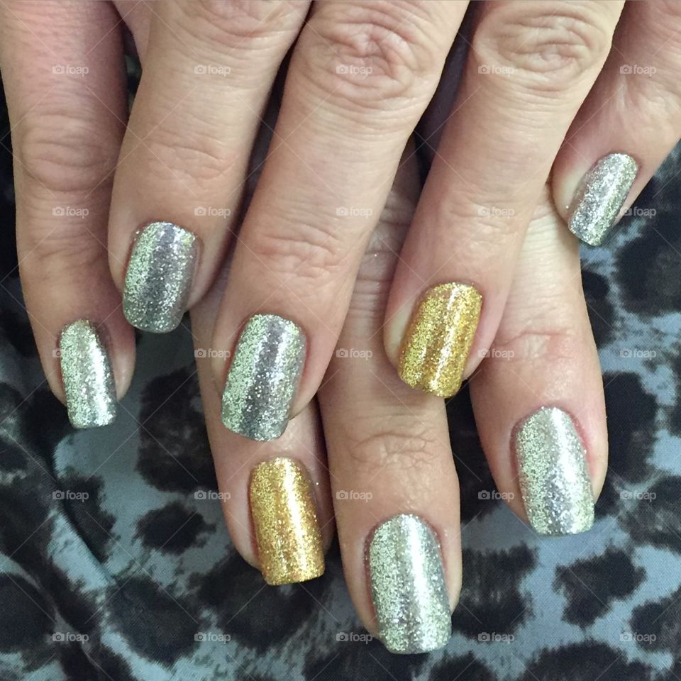 Silver and gold glitter nails with animal print background.