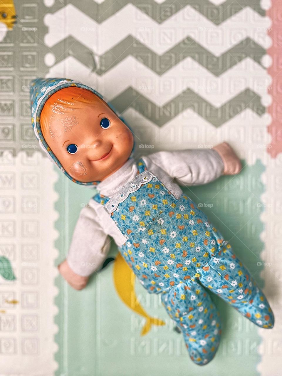 Smiling baby doll in playroom, toddler girls little baby doll, toy doll on playroom floor, happiness in a toy, a toy that makes children happy, emotion portrayed in a toy, smiling baby doll looking at the camera