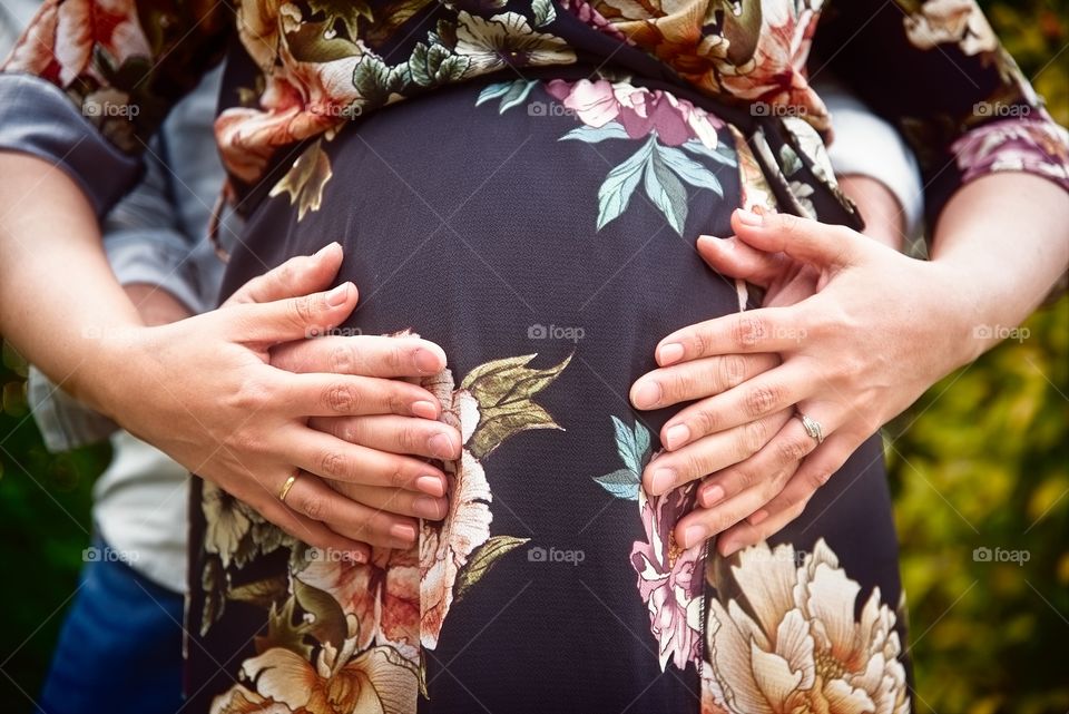 Pregnant couple put their hands on belly