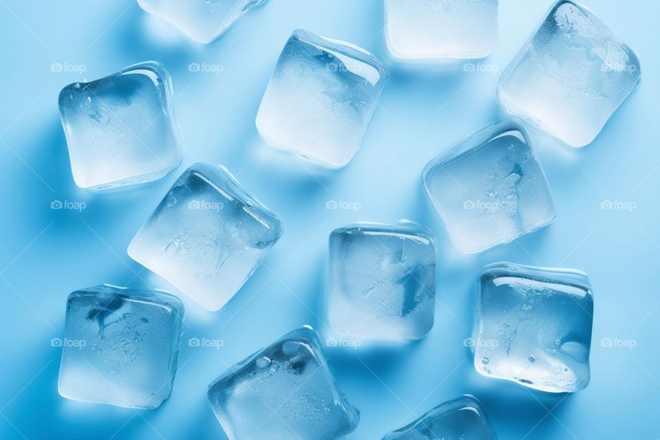 Fresh ice cubes to chill drink. Frozen pure water. Clear ice cubes background. Top view of ice pieces on table. Light blue color. Macro shot