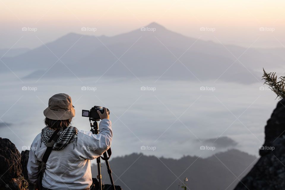 A journalist photographer taking picture of morning mist ocean on the Hill of Chiangrai tourist attraction