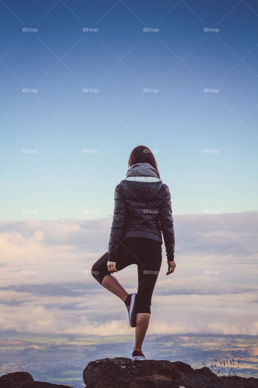 Woman balancing on rock against dramatic sky