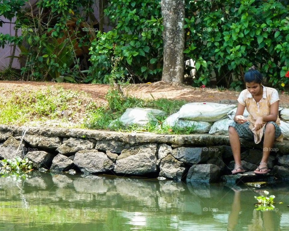 girl sitting by the river, India