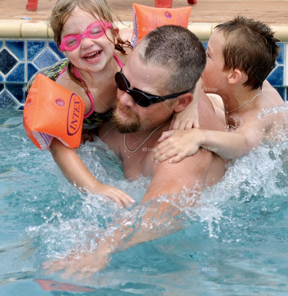 Father having fun with children in the swimming pool 