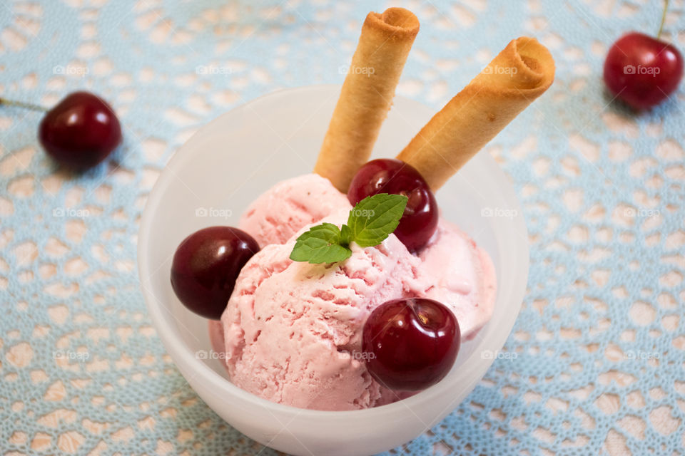 Bowl of ice cream with cherry and mint leaf