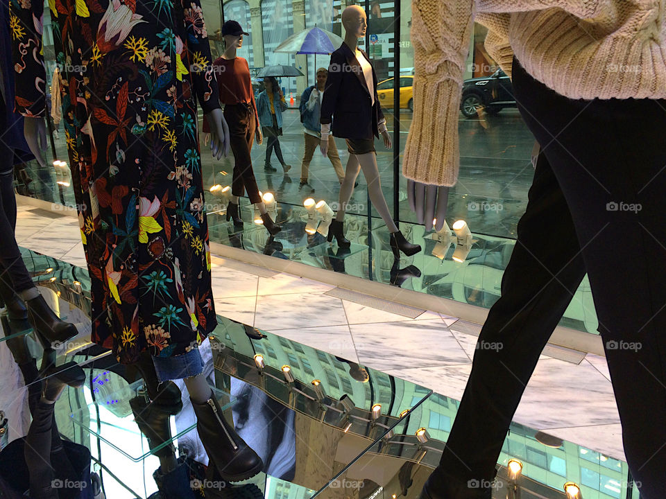 Shopping on a rainy day in New York. Looking through the window outside. A couple with umbrellas is walking by. 