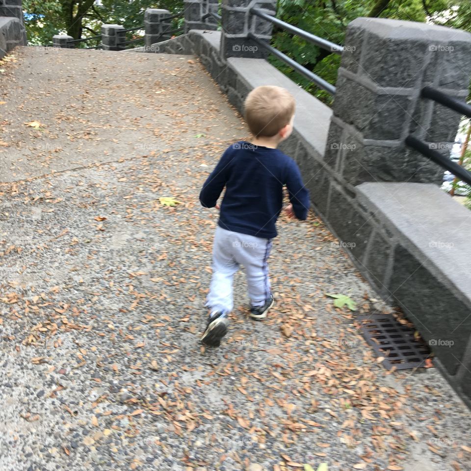 A boy running outside on the stone staircase