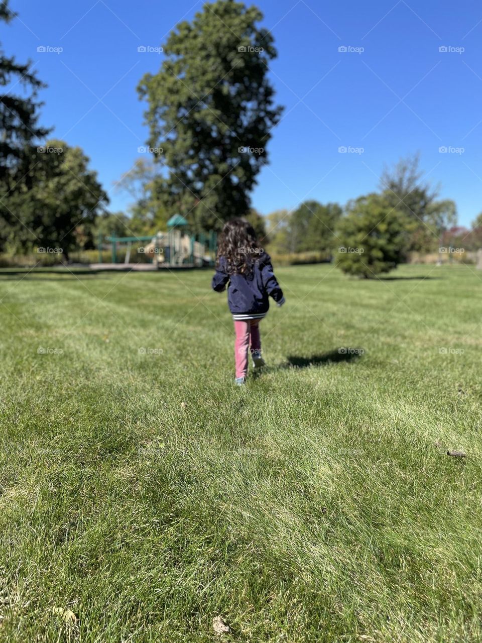 Little girl running towards park, toddler running in the park, little girl excited about playground equipment, playing in the park in the fall