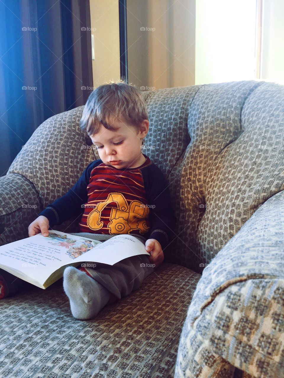 Boy sitting on armchair reading story book