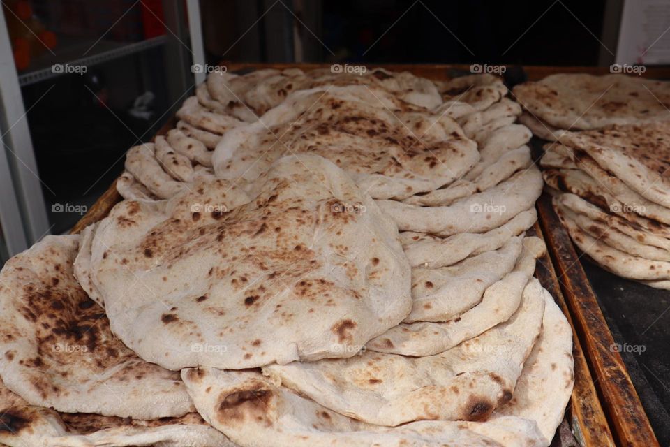 Piles of fresh hot pita bread in bakery 