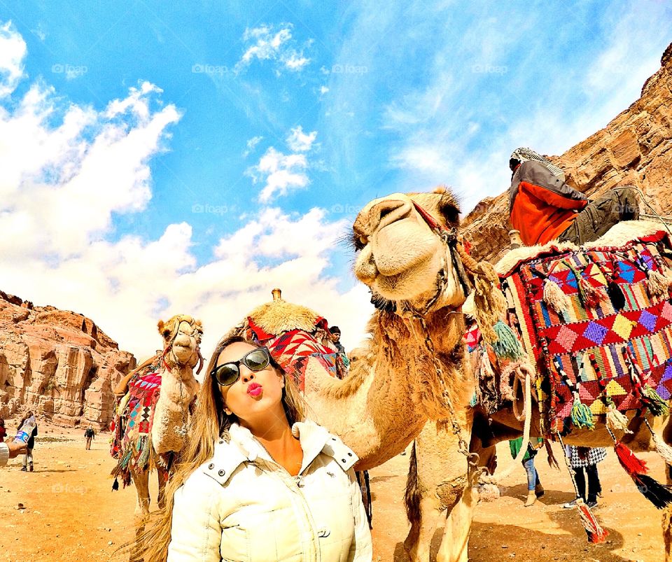 Woman standing in front of camel in desert