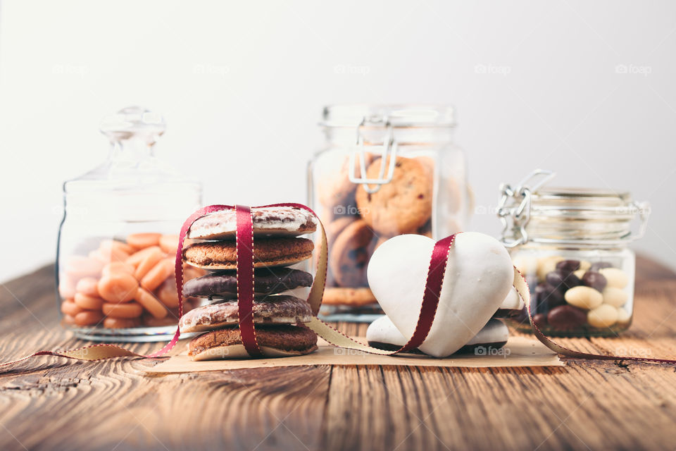 Gingerbread cookies, candies, cakes, sweets in jars on wooden table