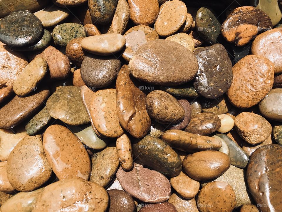 Full frame shot of wet rough brown rocks in natural day light, using for background