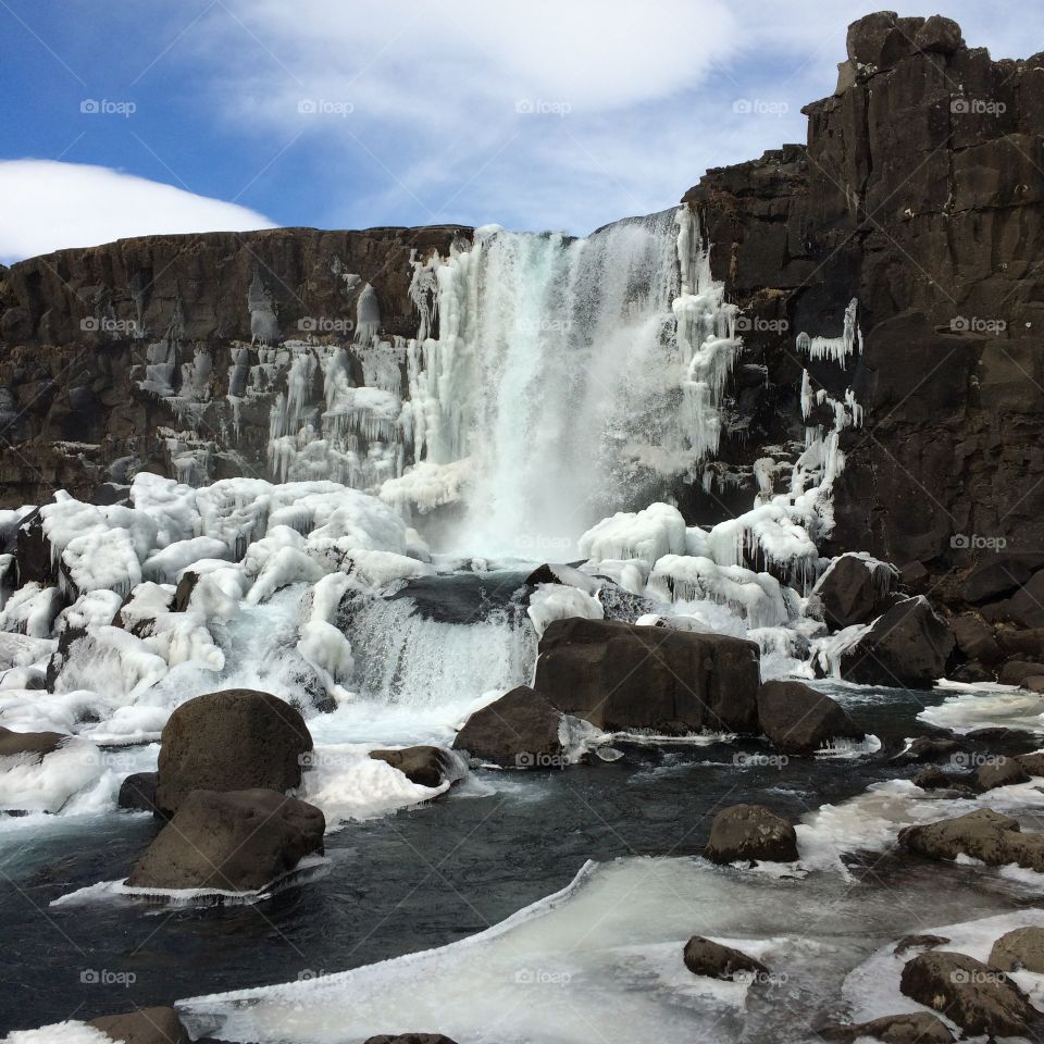Frozen waterfall with dramatic rocks and blue sky