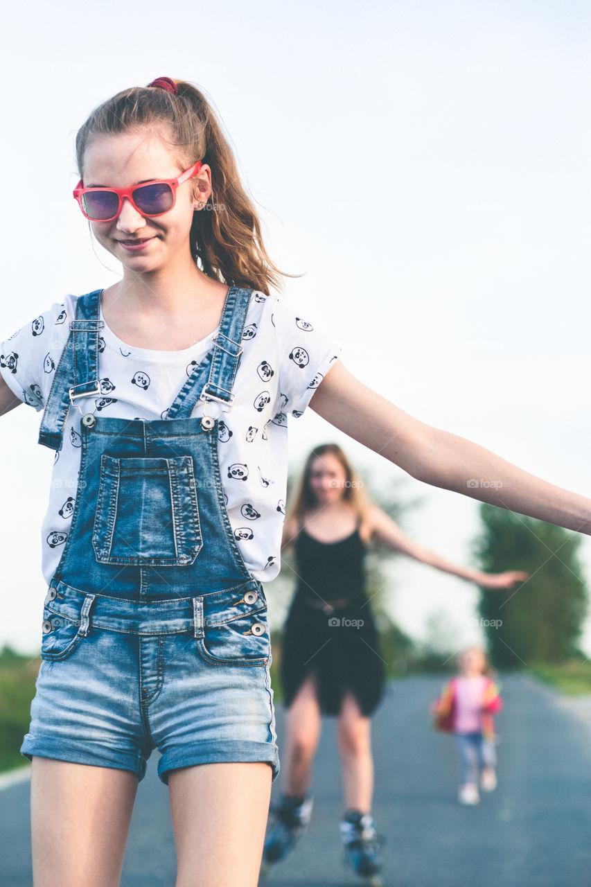 Teenage smiling happy girls having fun rollerskating together on summer day