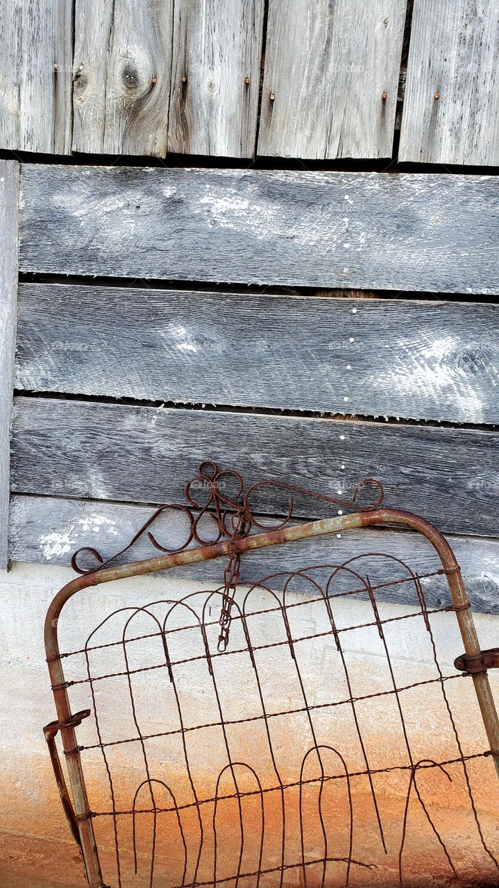 rusty fence leaning against weathered barn