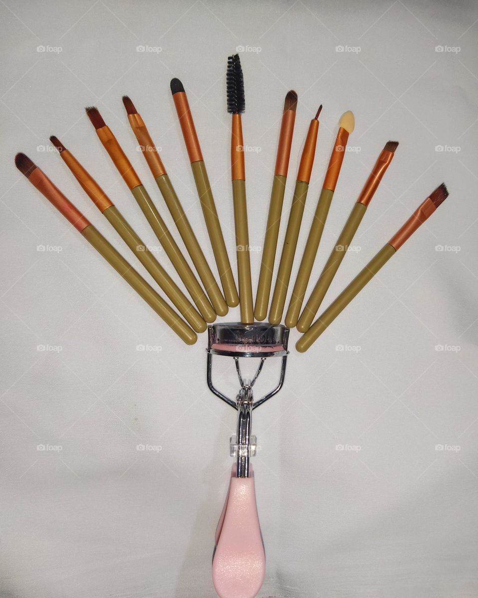 Makeup brushes and eyelash curler arranged in a beautiful pattern