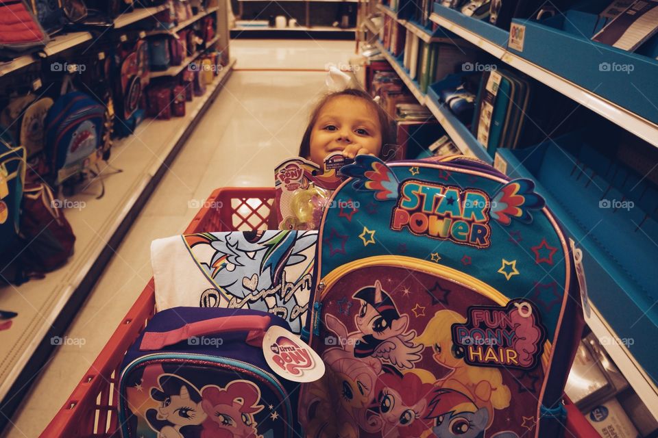 Little girl buying schoolbag in mall