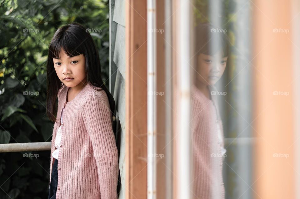 There is always a conflict between mind and soul, it depends on us what we choose...a reflection shot of a young little girl by the window.