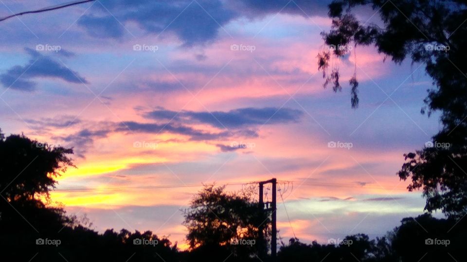 Illuminating sunrays shattered with crimson hues on wide spread horizon.