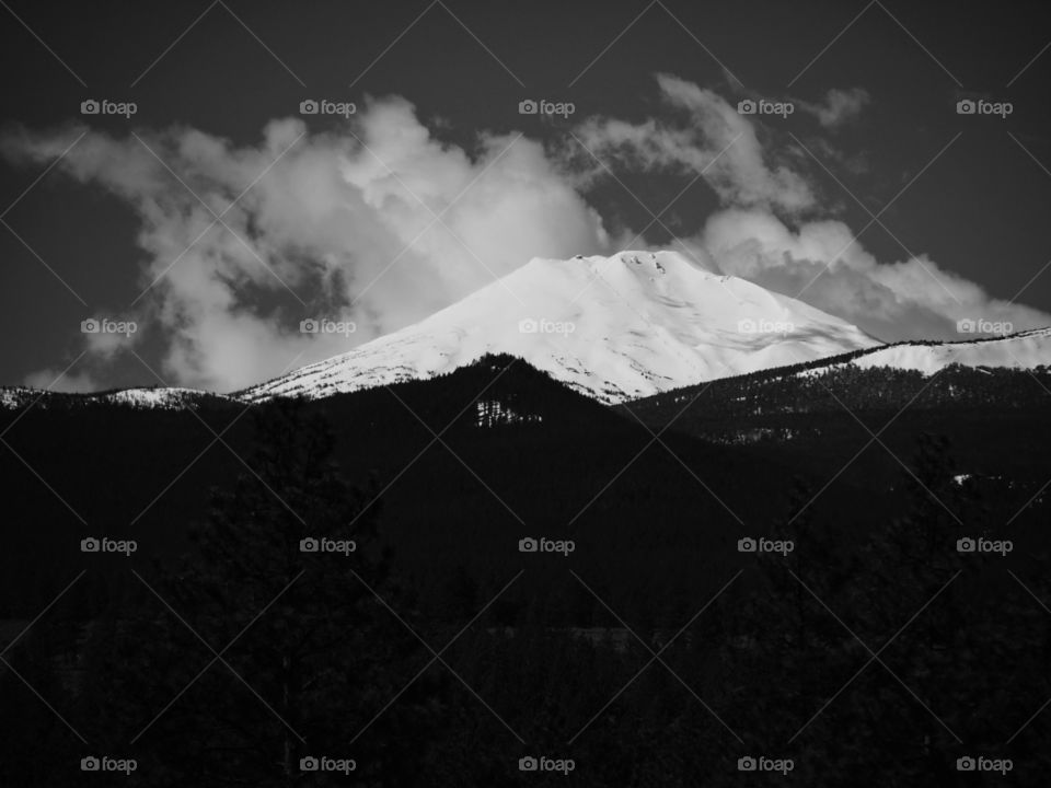 Beautiful clouds blow by snow covered Mt. Bachelor in Central Oregon on a sunny day. 