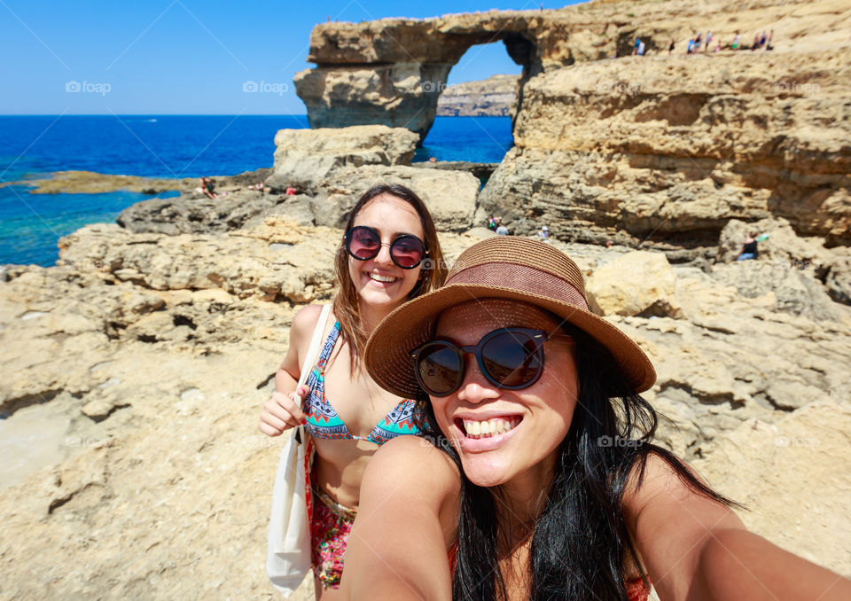 Two woman in bikini taking selfie at coastline