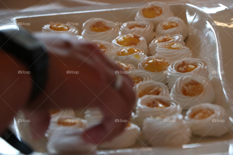 Human hand grabbing a meringue Pavlova 