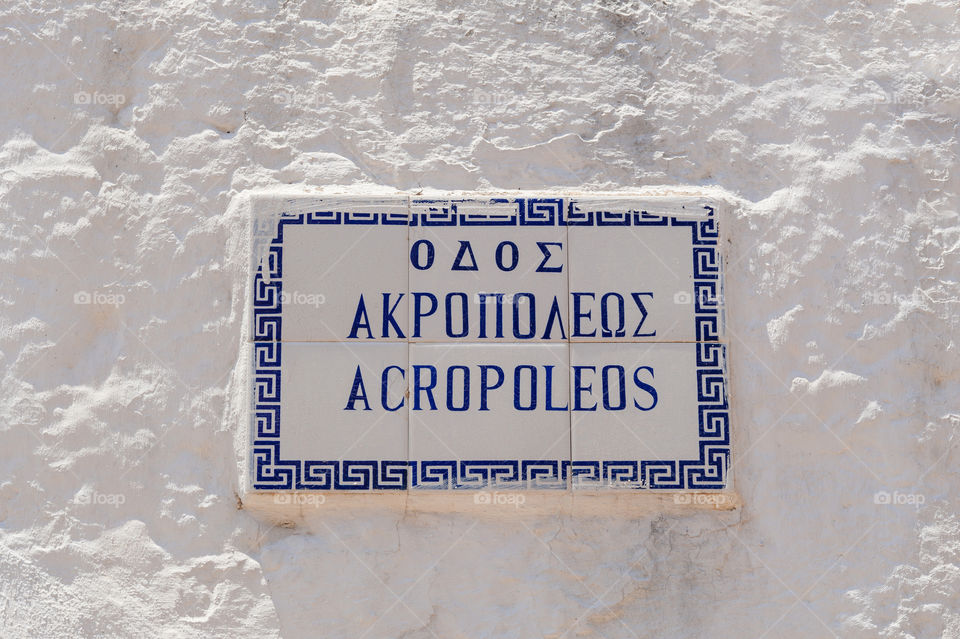 Acropolis street sign on whitewashed wall. Translation: Acropolis.