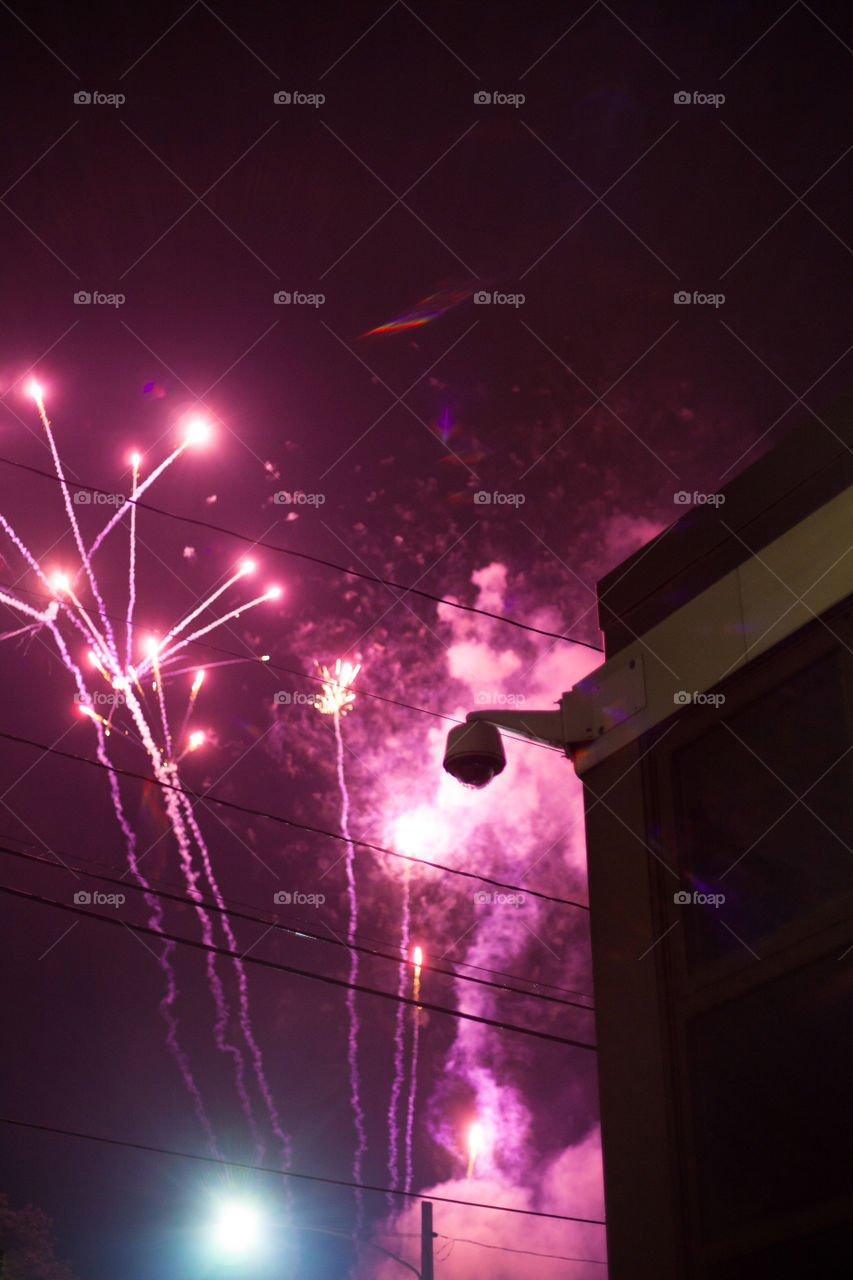 Purple fireworks behind a surveillance camera