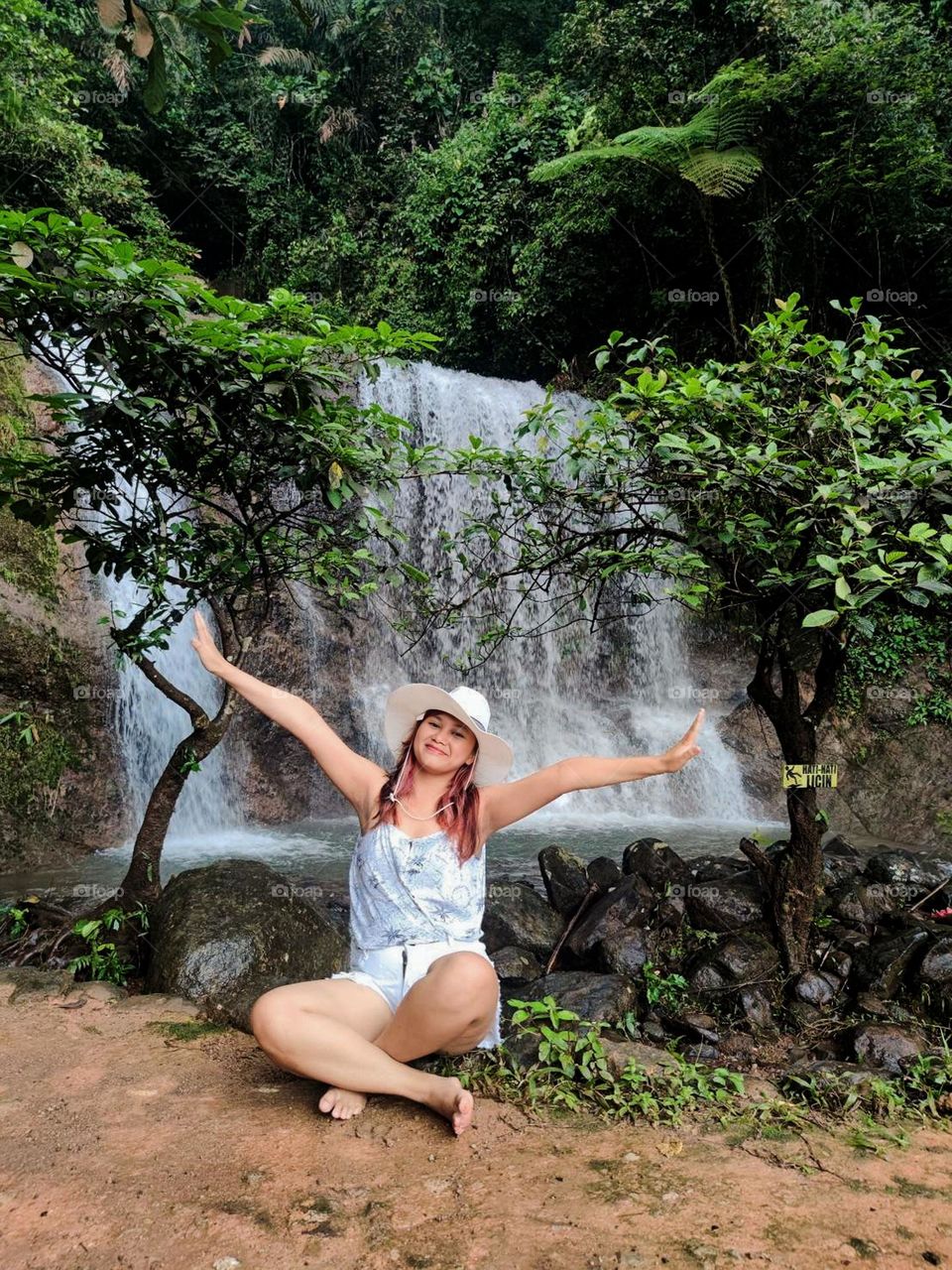 Portrait of woman sitting against waterfall