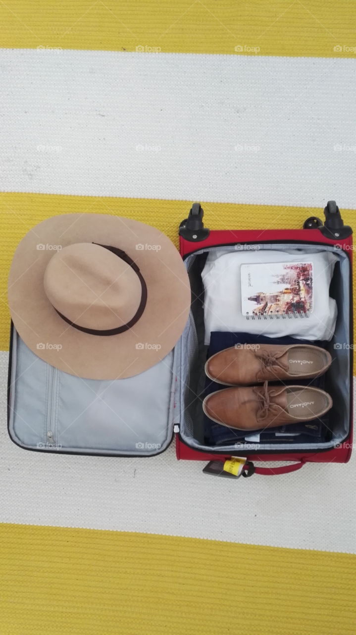 Packing simple way for a vacation. Big brown hat, brown shoes, a book. Light colorful.
