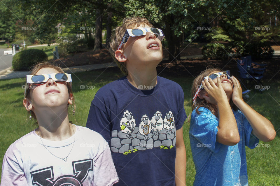 Group of children looking at solar eclipse in park