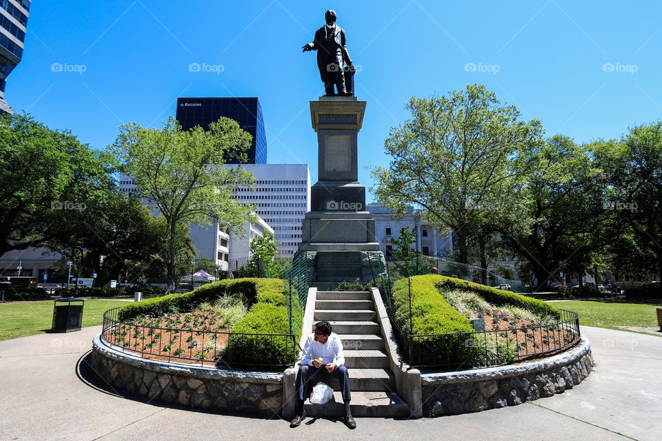 Man sitting at the statue in the public park 